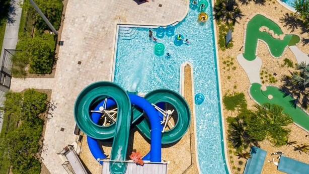 An aerial view of a water park with a large pool, two water slides, and a wave pool.