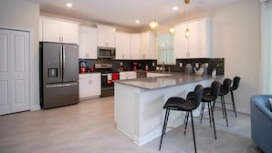 A modern kitchen with white cabinets, stainless steel appliances, and a central island with bar stools.