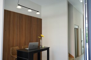 A modern office space with a wooden panel wall, a desk with a laptop, two chairs, and a vase with yellow flowers. - VILLAGRADO Suites AT3LLaves (Grado)