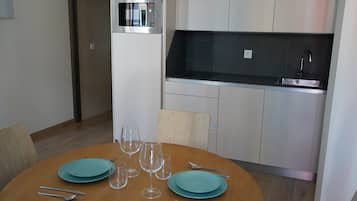 Una cocina moderna con microondas integrado, encimera negra y pileta de acero inoxidable.