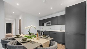 A modern kitchen with dark cabinets, a microwave, and a large refrigerator. - 3 Bed with Balcony | City Centre (Greater Manchester)