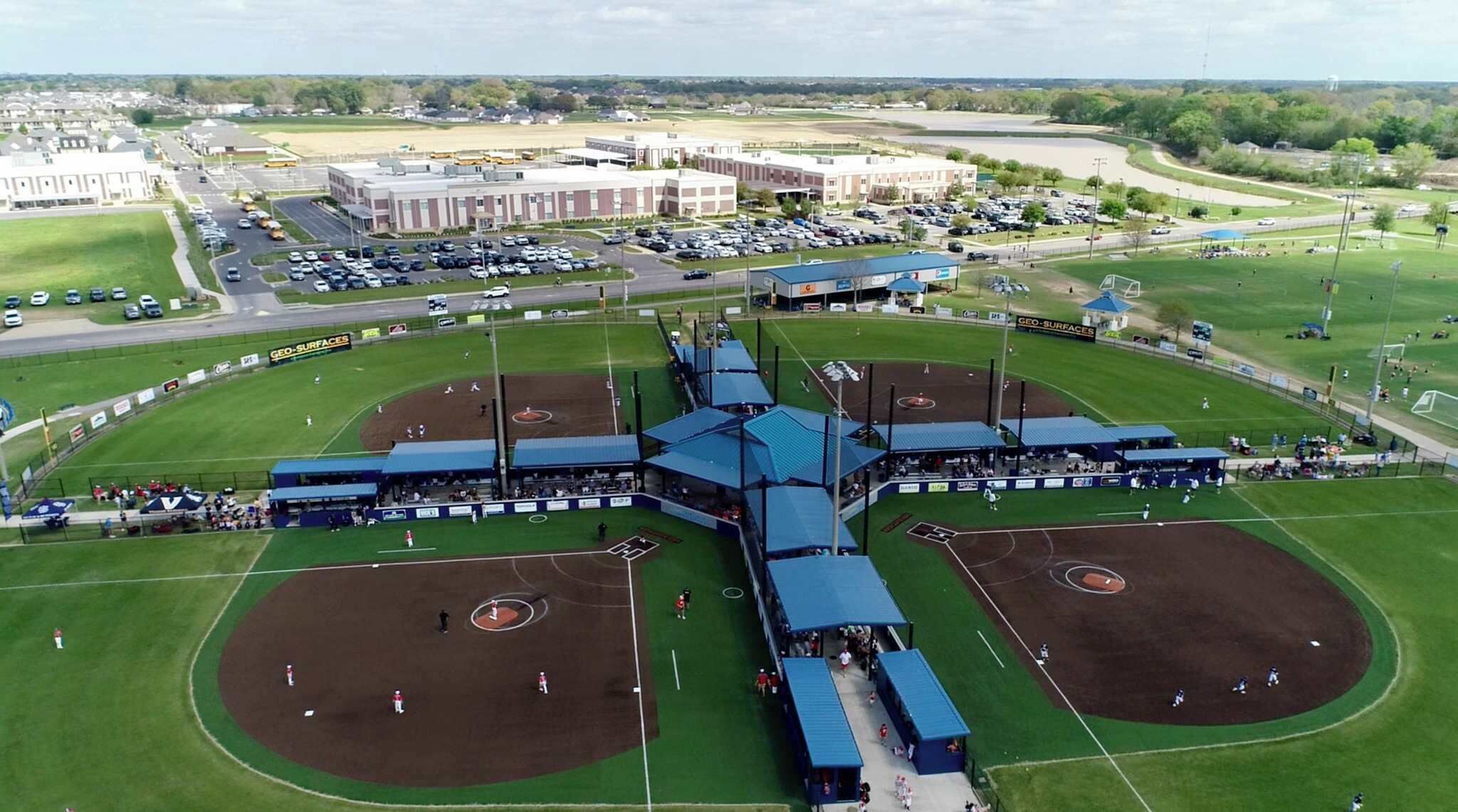 Un stade de baseball doté de plusieurs terrains, d’un vaste parking et d’un bâtiment imposant en arrière-plan.