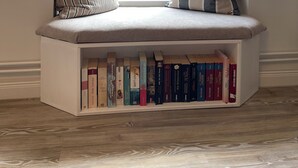 A built-in bench with a bookshelf underneath, positioned by a window with a view of greenery outside. - Hermine vacation apartment with far-reaching views of nature (Soltau)