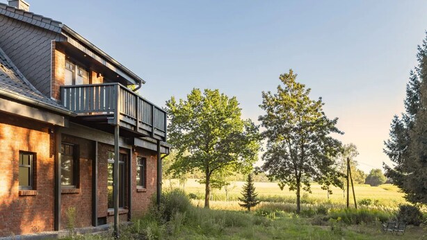 A modern house with a brick exterior, a balcony, and a view of a grassy field with trees. - Hermine vacation apartment with far-reaching views of nature (Soltau)