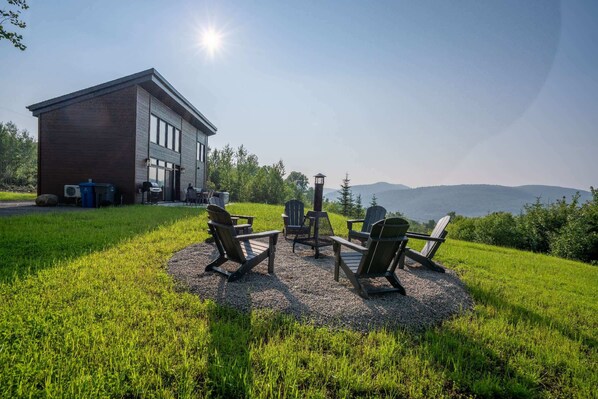 A building with a gravel patio and Adirondack chairs.
