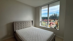 Un dormitorio con un ventanal grande, una cama y una lámpara de techo.
