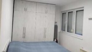 Un dormitorio con cama, armario y ventana.