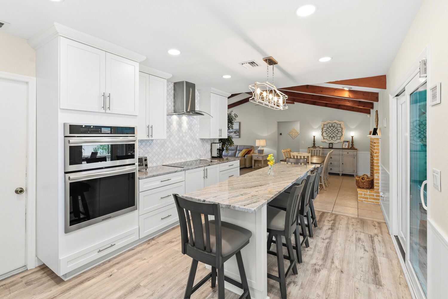 A modern kitchen with white cabinets, a marble countertop, and a central island with bar stools.