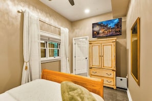 A bedroom with a bed, a wardrobe, a television, and a door.