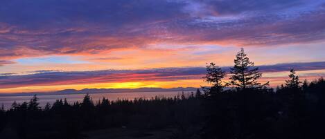 A sunset over a forested landscape with a clear view of the horizon.