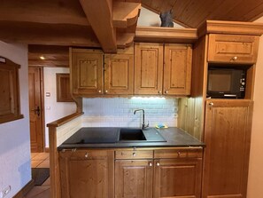 A kitchen with wooden cabinets, a black countertop, a sink, and a microwave. - 3rd floor, view ski slopes, swimming pool, balcony, tv, ski locker, 76m², Les Saisies (Les Saisies)