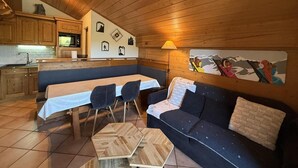 Een knus interieur van een chalet met een eethoek, een bank en een keuken.