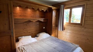 Ein Zimmer aus Holz mit einem Bett, einem Fenster und einer Tür.