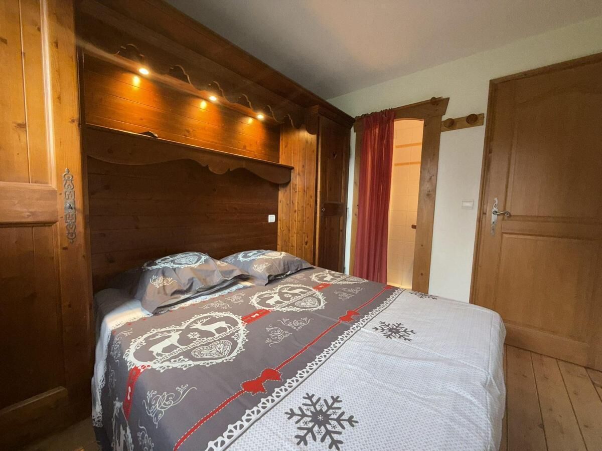 A wooden room with a bed, wooden walls, and a door.