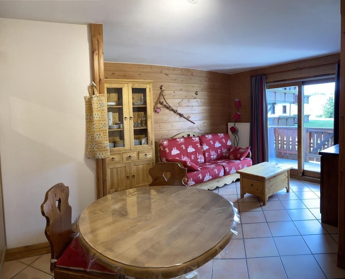 Ein gemütliches Zimmer mit einem Holzesstisch, einer Couch und einer Vitrine.