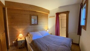 A cozy bedroom with a wooden headboard, a single bed, a nightstand with a lamp, and a framed picture on the wall.