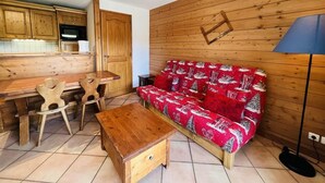 A cozy living room with a wooden sofa, a wooden coffee table, and a dining area with wooden chairs and a wooden table. - 100m from ski slopes, 2nd floor, swimming pool, balcony, tv, ski locker, 8m², Les Saisies (Les Saisies)