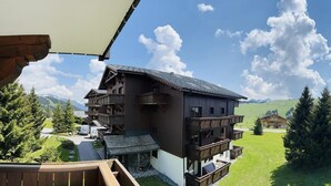 A chalet-style building with a balcony, surrounded by a lush green landscape and mountains in the background. - 100m from ski slopes, 2nd floor, swimming pool, balcony, tv, ski locker, 8m², Les Saisies (Les Saisies)
