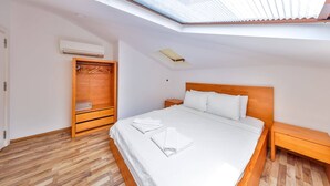 A bedroom with a skylight, a wooden wardrobe, a bed with white linens, and a nightstand. - THE PENTHOUSE WİTH TERRACE (Kas)