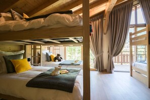 Una habitación tipo cabaña con literas, una ventana con cortinas y vistas a la vegetación.