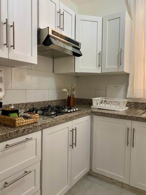A kitchen with white cabinets, a gas stove, and a stainless steel range hood.