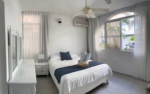 A bedroom with a bed, a nightstand, a ceiling fan, an air conditioner, and a window with curtains.
