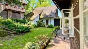 Una casa rústica con escaleras de piedra, un jardín cuidado y una terraza de madera.