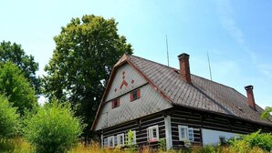 Una casa de madera tradicional con un techo pronunciado, varios chimeneas y un árbol grande al fondo.