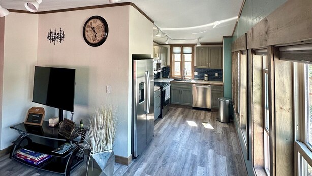A modern kitchen with stainless steel appliances, a built-in oven, and a dishwasher. There is a large window providing natural light and a view of the outdoors. - Livingston MT Paradise Unit B (Livingston)