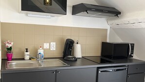 A compact kitchen with a built-in microwave, a coffee maker, and a dishwasher. - Cosy furnished studio in a quiet location near the Cathedral (Orléans)