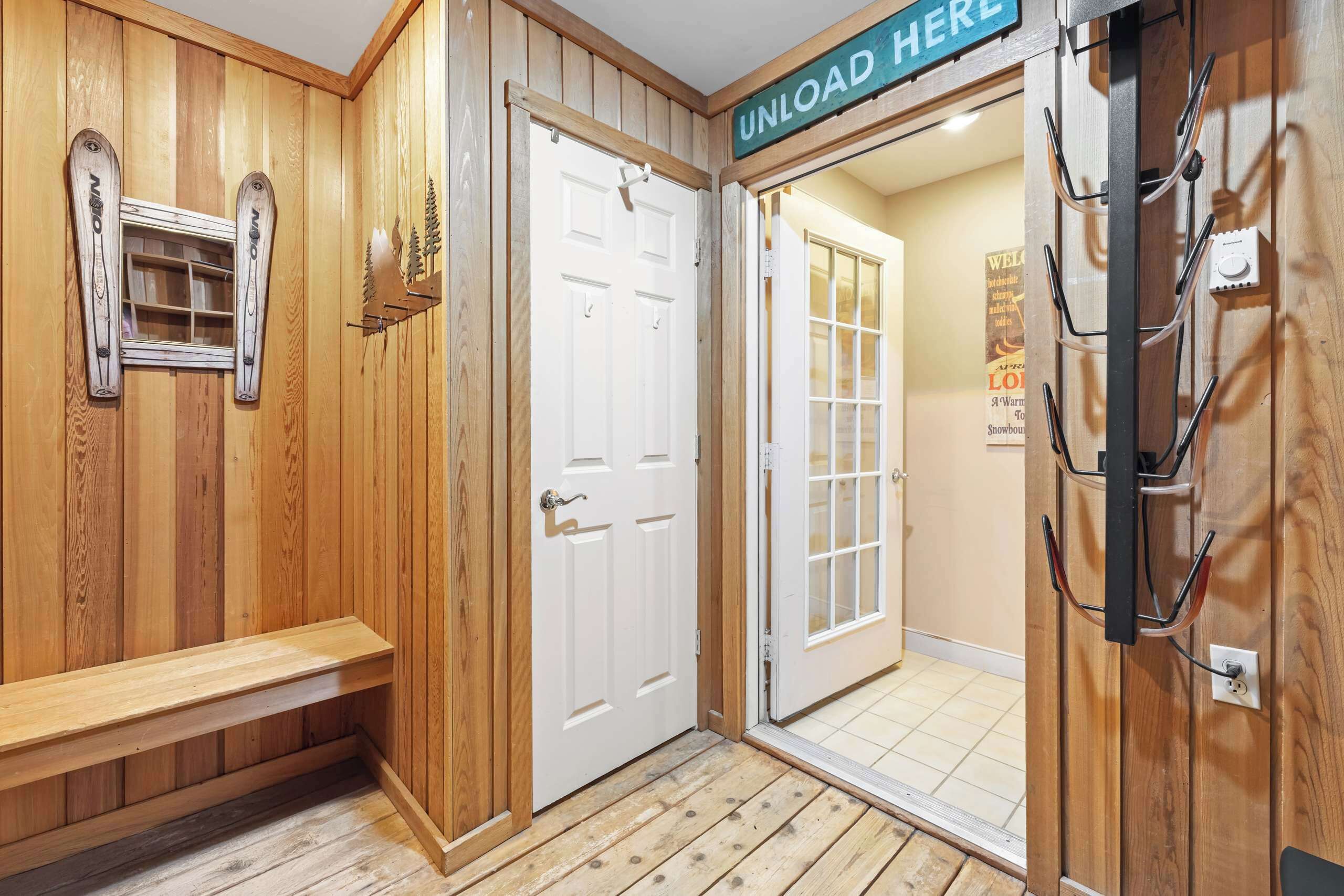 Un intérieur en bois avec un banc, une porte portant l’inscription « DÉCHARGEMENT ICI » et un support fixé au mur.