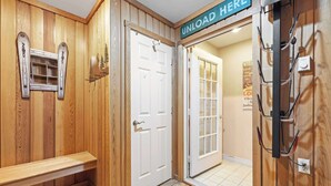 A wooden interior with a bench, a door labeled "UNLOAD HERE", and a wall-mounted rack.