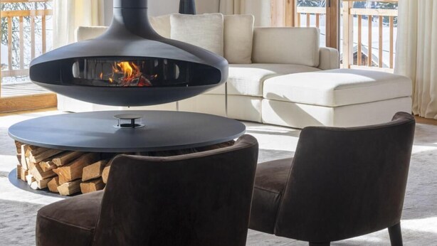 A cozy living room with a modern fireplace, a sofa, and a dining table.