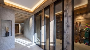 A modern interior with a wooden ceiling, large sliding glass doors, and a ski rack.