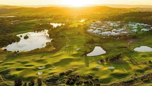 Un campo de golf con búnkeres y obstáculos acuáticos, rodeado de edificios residenciales y un lago.