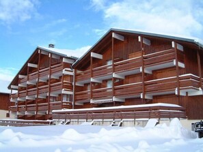 A wooden chalet with multiple balconies and a snow-covered ground. - 250m from resort center, 2nd floor, view ski slopes, terrace, tv, ski locker, 24m², Les Saisies (Les Saisies)