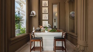 A room with two wooden chairs facing a table with a vase of flowers and a small statue. - Ali Grand Hotel (Vientiane)