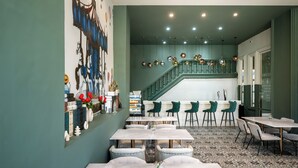 A restaurant with a green interior, marble tables, and a staircase leading to an upper level. - Ali Grand Hotel (Vientiane)