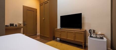 A hotel room with a bed, a television, a minibar, and a wardrobe.