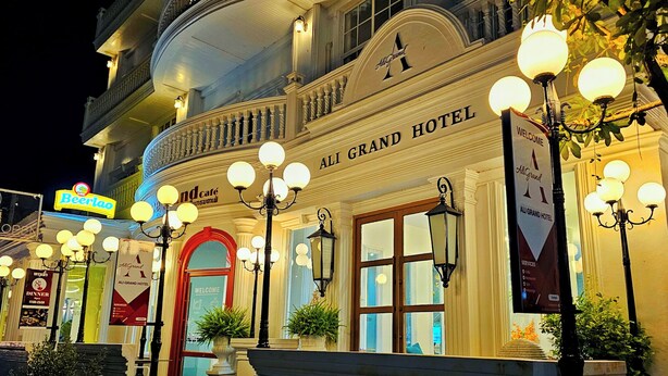 The exterior of the Ali Grand Hotel with a prominent entrance, illuminated by multiple light fixtures, and a signboard displaying the hotel's name. - Ali Grand Hotel (Vientiane)
