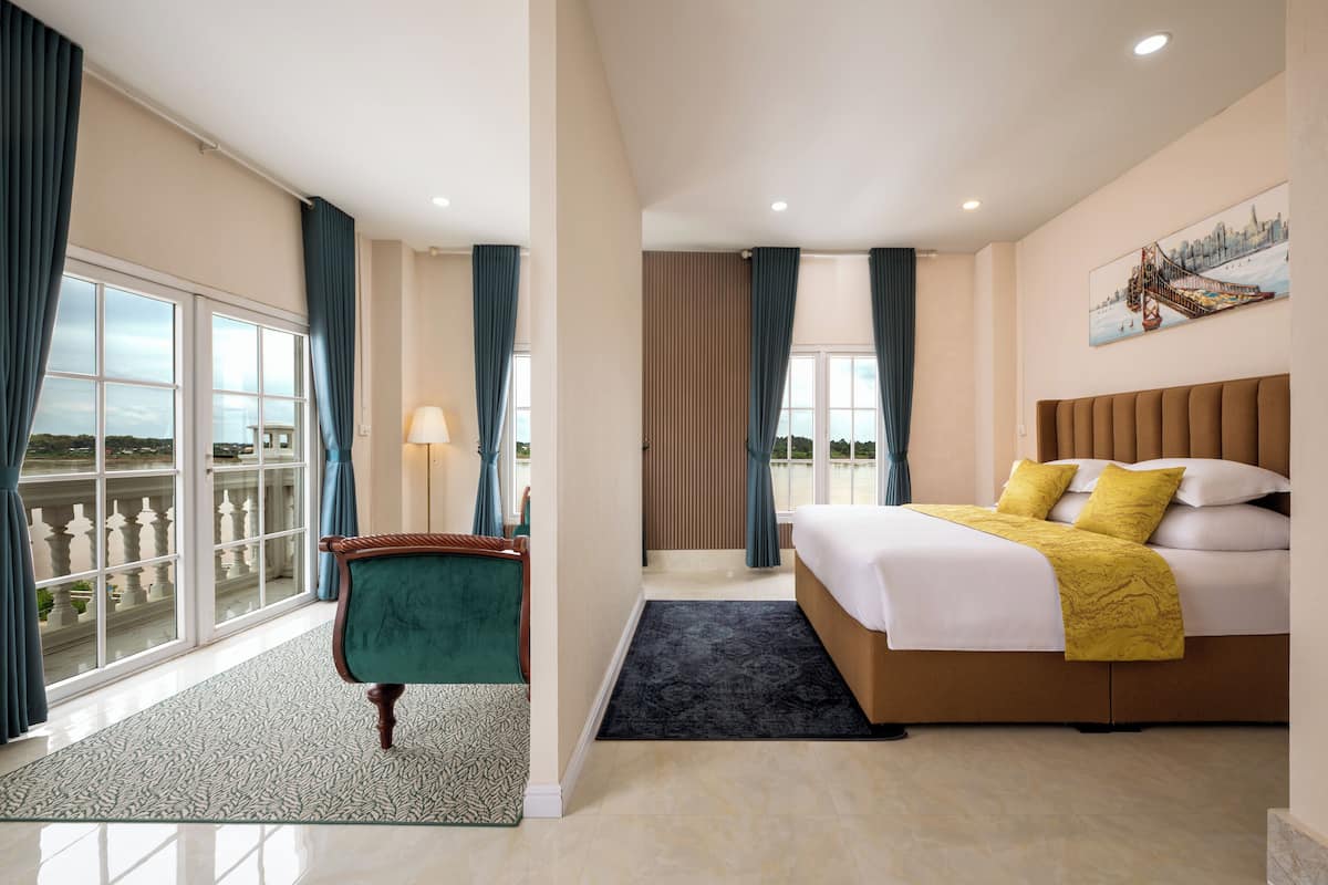 Ett hotellrum med en stor säng, utsikt över omgivningarna, en balkong och ett fönster med gardiner.