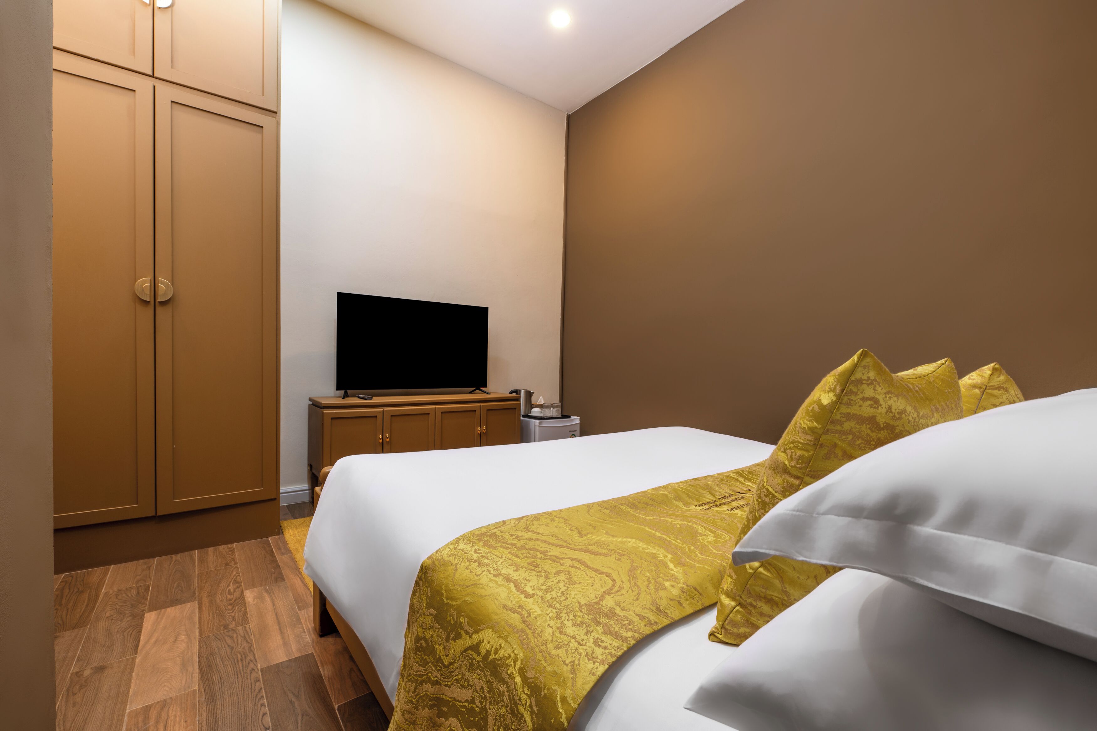 A hotel room with a bed, a television, a wardrobe, and a bedside table.