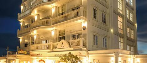 Un hotel de varios pisos con una entrada imponente, varios balcones y una fachada bien iluminada.