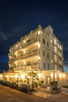 Un hotel de varios pisos con una entrada imponente, varios balcones y una fachada bien iluminada.