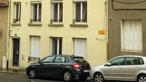 A multi-story building with a flat facade, multiple windows with white shutters, and a small balcony on the second floor. - Le Duplex d'Abi, quiet, overlooking courtyard, close to the center of Saint Étienne (Saint-Étienne)