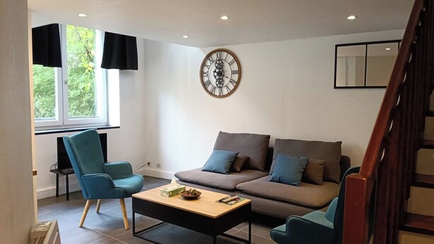 A modern living room with a sofa, two armchairs, a coffee table, a wall clock, and a window with blinds. - Le Duplex d'Abi, quiet, overlooking courtyard, close to the center of Saint Étienne (Saint-Étienne)