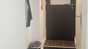 A narrow hallway with a dark door, a map on the wall, and a pair of shoes on the floor. - Le Duplex d'Abi, quiet, overlooking courtyard, close to the center of Saint Étienne (Saint-Étienne)