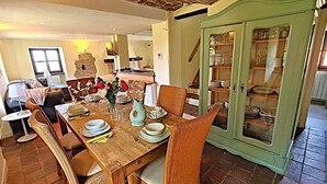 A dining area with a wooden table set for four, surrounded by wicker chairs. A green cabinet with glass doors is visible in the background. - Wonderful property in a fantastic location. Family-friendly. Il Roseto I (Somano)