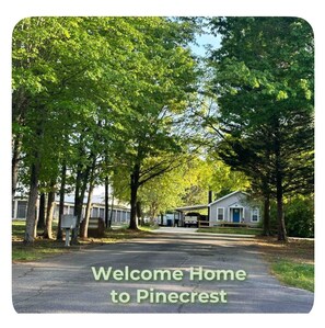 A residential street lined with trees and a house with a porch.