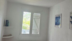 A room with a white radiator, a window with a view, and a shelf with books. - Charming T1 bis apartment in Collobrières (Collobrières)